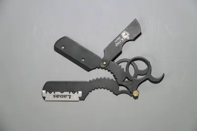 A mini straight razor with swappable blade and finger ring pulled apart to show how the swappable blade feature works
