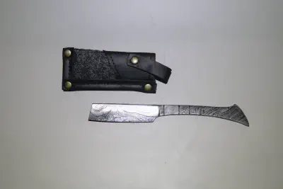 A damascus straight razor next to its case